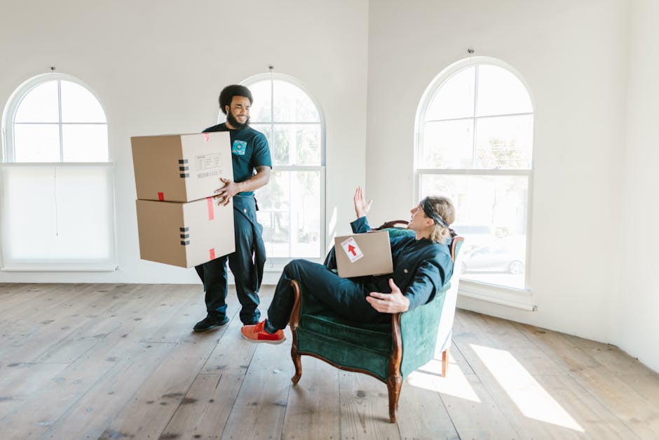 Two people handling packages in a bright room with large windows.