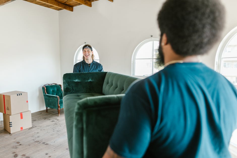 Man looking at himself in a mirror while sitting on a green couch.